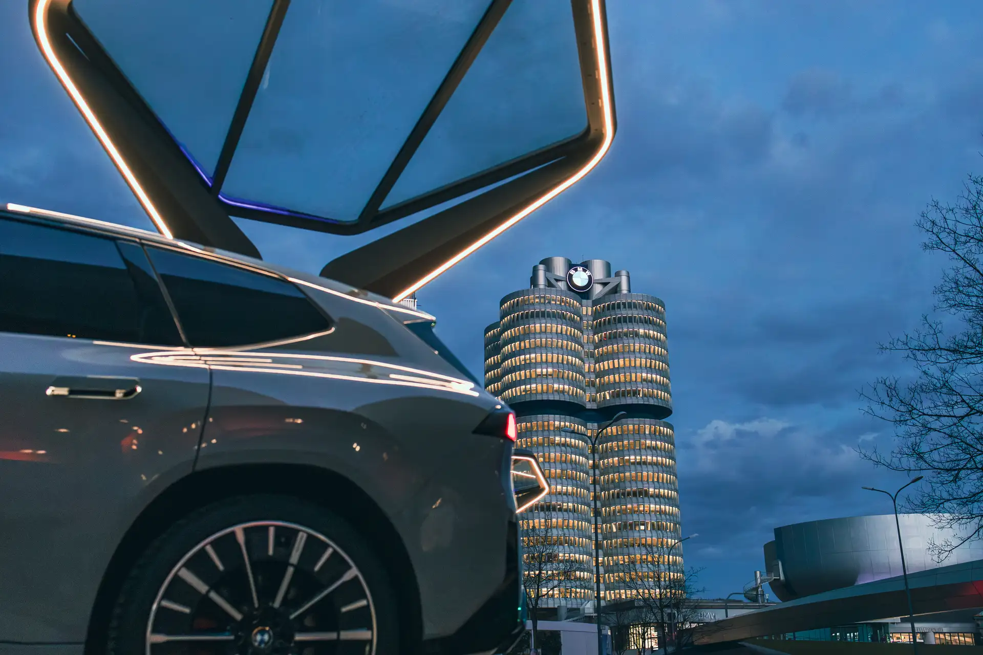 BMW iX3 Rental Car from CarVia standing in front of the BMW HQ in Munich